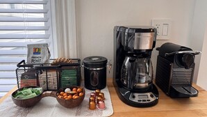 En køkkenbordplade med kaffemaskine, slow cooker, foodprocessor og diverse køkkenredskaber.