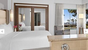 Une chambre d’hôtel avec un grand lit, une salle de bain avec baignoire et une vue sur les palmiers.