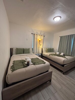 Un dormitorio con dos camas, una lámpara de pie y una luz en el techo.