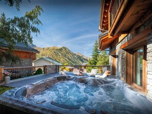 Ein Whirlpool mit Bergblick, Holzliegen und Steinsäulen.