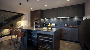Una cocina moderna con armarios de madera oscura, una isla central y un soporte para copas de vino.