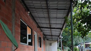 A covered walkway with a brick wall, potted plants, and a tiled floor.