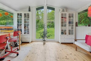 Ein Zimmer mit großem Fenster, einem Blumentopf, einem weißen Schrank und einem roten Sessel.