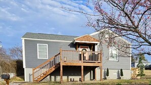 A two-story house with a front porch, a small deck, and a mailbox. - ★ Superhost Rated ★ Lily of the Valley Retreat - Steps to Downtown (Kingsport)