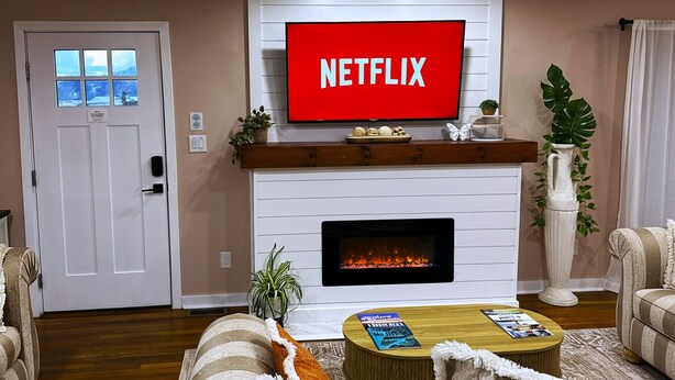 A living room with a fireplace, a television mounted above it displaying 'NETFLIX', and a door with a window. - ★ Superhost Rated ★ Lily of the Valley Retreat - Steps to Downtown (Kingsport)