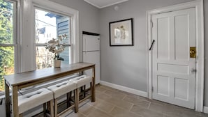 A hallway with a white door, a framed picture on the wall, and a table with a bench. - Tranquil, Centrally Located 3-bedroom apartment in Buffalo (Buffalo)