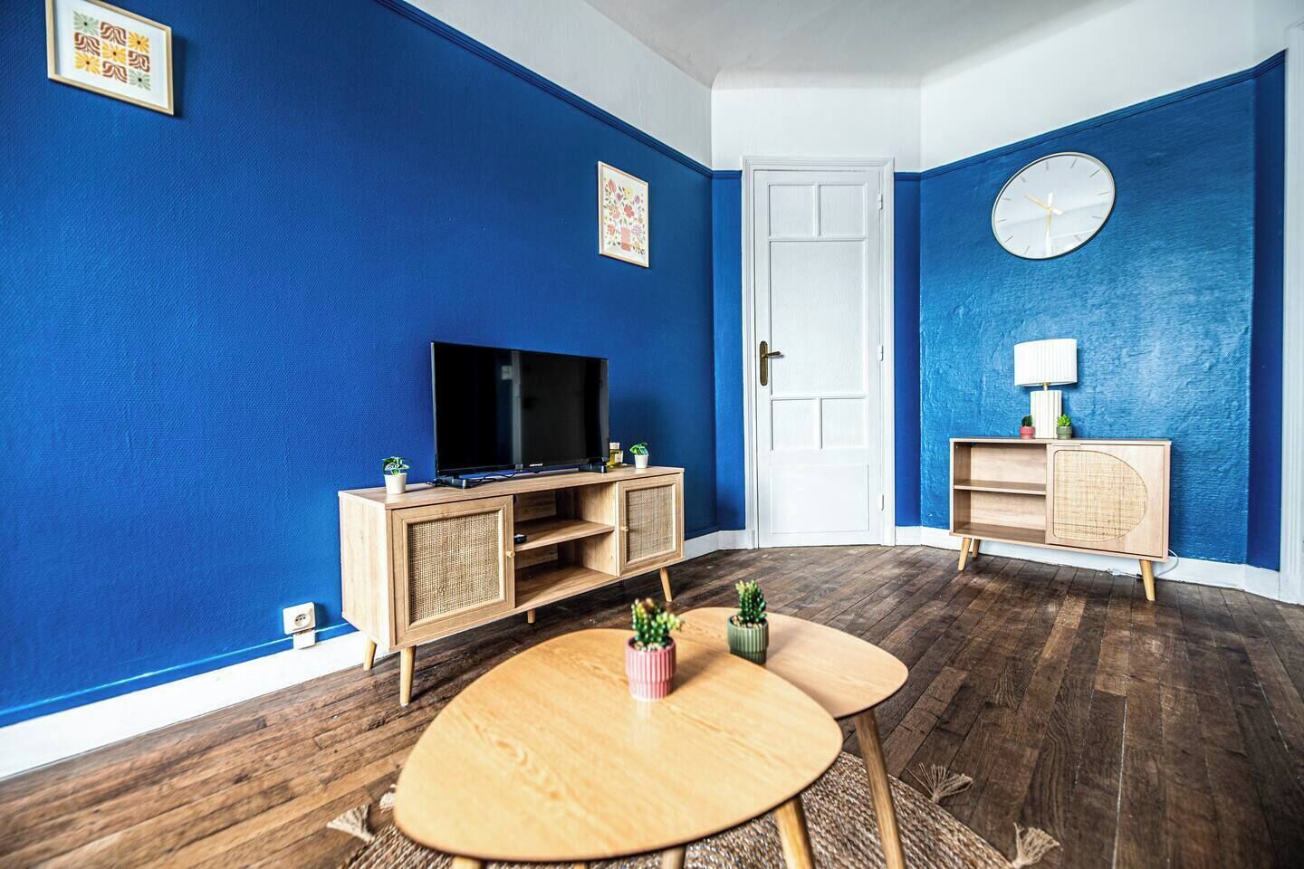 A room with a TV, wooden cabinet, round table, and blue walls.