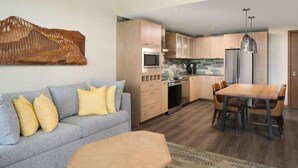 Eine moderne Küche mit Holzausstattung, einem Esstisch und einer Couch mit gelben Kissen.