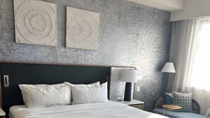 Ein großes Bett mit weißer Bettwäsche, ein dunkles Kopfteil und eine strukturierte Wand dahinter.