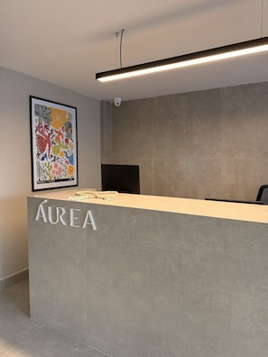 A reception desk with a sign reading "AUREA" and a framed artwork on the wall. - Estudio Aurea Bauten 202 (João Pessoa)