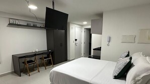 A modern bedroom with a large bed, a desk, and a TV. - Estudio Aurea Bauten 202 (João Pessoa)