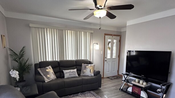 Una sala de estar con sofá, sillón reclinable, mueble para televisor y ventilador de techo.