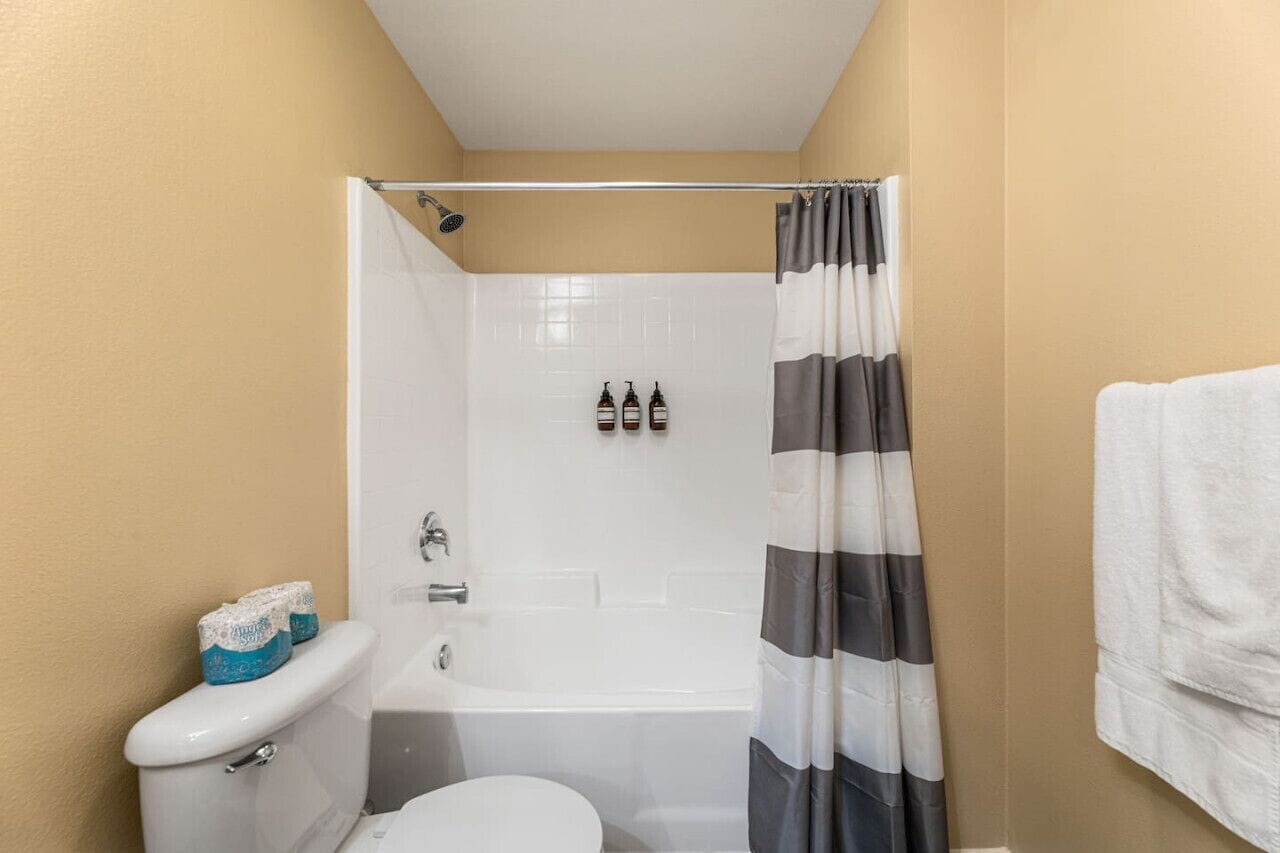 A bathroom with a toilet, a bathtub, and a shower curtain.