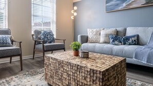 A living room with a grey sofa, two armchairs, a wooden coffee table, and a painting on the wall. - Charming Family Home | Heart of OC | Free Parking (Orange)