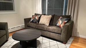 A living room with a brown sofa, a round coffee table, and patterned rugs. - Litchfield Retreat, Wineries, Foliage & Skiing (Torrington)
