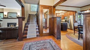 Ein geräumiger Wohnbereich mit Kamin, einer Treppe zu einer weiteren Ebene und einer Küche mit modernen Geräten.