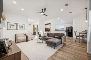A modern living room with a sectional sofa, a coffee table, and a dining area with a table and chairs. - Welcoming Retreat in McKinney, TX (McKinney)