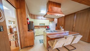 Une cuisine compacte avec des meubles en bois, un îlot central doté de sièges et un extincteur visible.