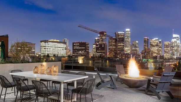 Terraço no telhado com mesa e cadeiras, lareira e vista para o horizonte urbano.