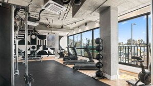 Uma academia moderna com equipamentos de ginástica, janelas amplas e vista para a cidade.