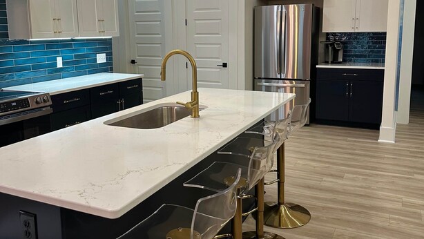 A modern kitchen with a central island, stainless steel appliances, and a bar area with stools.