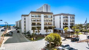 A multi-story hotel with balconies, a parking lot, and a view of the ocean. - 1st-Floor 2BR Condo | Myrtle Beach Resort | Pools, Waterpark & Beach | Sleeps 8 (Myrtle Beach)