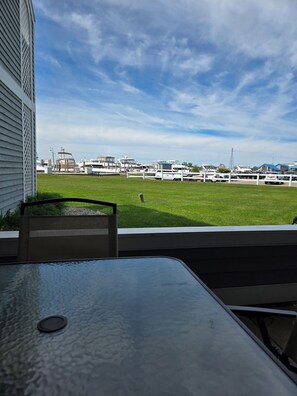 A view of a marina with boats docked, a grassy area, and a building with a sloped roof. - Charming 1 bedroom, 1 bathroom condo with spacious kitchen and walkout patio (Spring Lake)