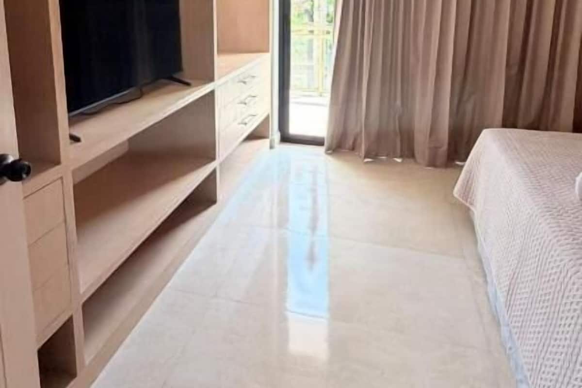 Une chambre d’hôtel avec un lit, une télévision, une armoire et une fenêtre avec des rideaux.