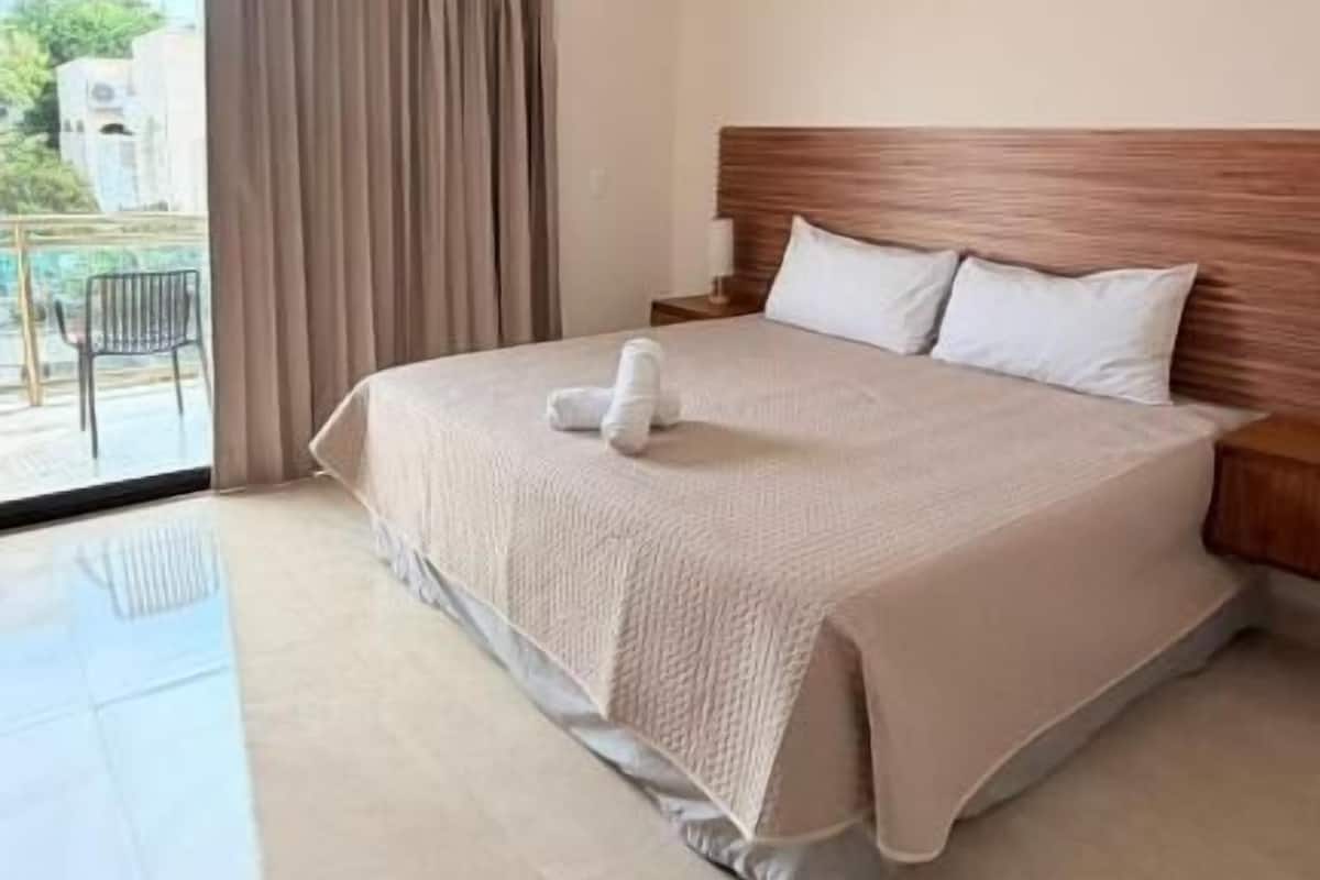 Une chambre d’hôtel avec un lit, une fenêtre avec des rideaux, un balcon et un appareil de climatisation.