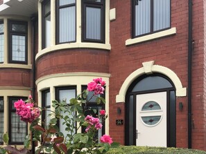 Un bâtiment à deux étages avec une porte blanche et une plaque noire portant le numéro « 66 ».