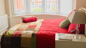 A bedroom with a bed, a nightstand, a lamp, and a window with blinds. - Traditional Family Home, Driveway & Gardens -  Preston, Samlesbury, M6, M55,M61, (Preston)