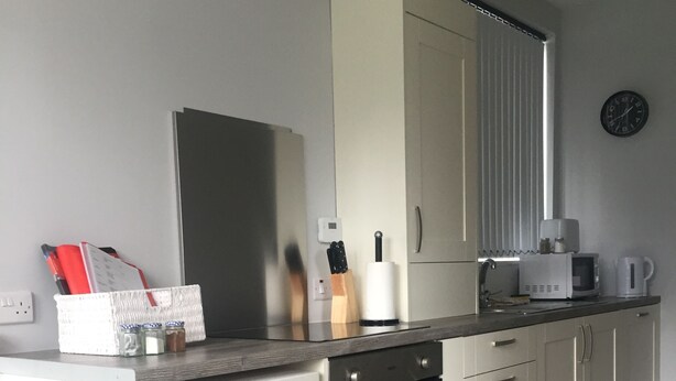 Une cuisine moderne équipée d’un lave-vaisselle, d’un four et de meubles blancs.