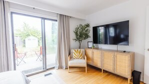 A modern room with a bed, a TV on the wall, a wooden cabinet, and a chair with a decorative pillow. - Private 2-BR Suite w/ Patio (Mississauga)