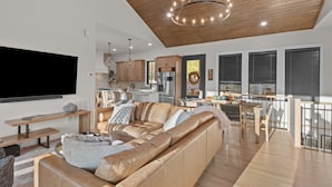 Ein großzügiger Wohnbereich mit einer großen Ledersofa, Holzboden und einer modernen Küche im Hintergrund.