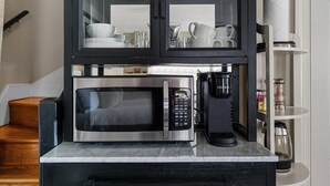 Eine Küche mit Mikrowelle, Kaffeemaschine und einem Schrank mit Geschirr.