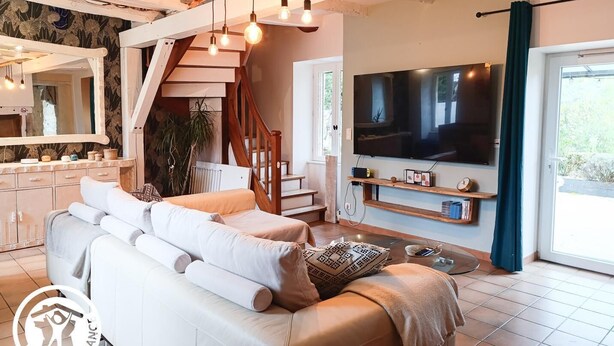 A modern living room with a sofa, TV, and wooden staircase.