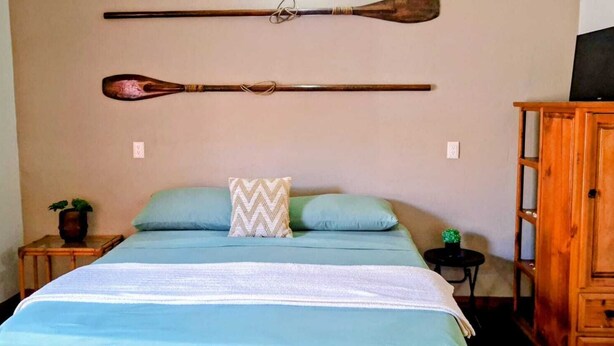 Ein Schlafzimmer mit einem Bett, einem Holzschrank und zwei an der Wand hängenden Schlägern.
