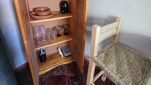 Ein Holzregal mit verschiedenen Gegenständen, darunter Tassen, Schüsseln und Gläser.