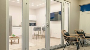 Una cocina moderna con armarios blancos, un microondas y una pequeña mesa con una planta.