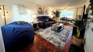 A cozy living room with a sofa, a chair, a coffee table, and a dining area with a table and chairs. - Cozy Elevated Luxury - King Bed, Coffee Bar, Sleeps 5 (Springfield)