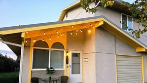 A house with a covered porch, a garage, and a small outdoor seating area with chairs and a table. - Cozy Elevated Luxury - King Bed, Coffee Bar, Sleeps 5 (Springfield)