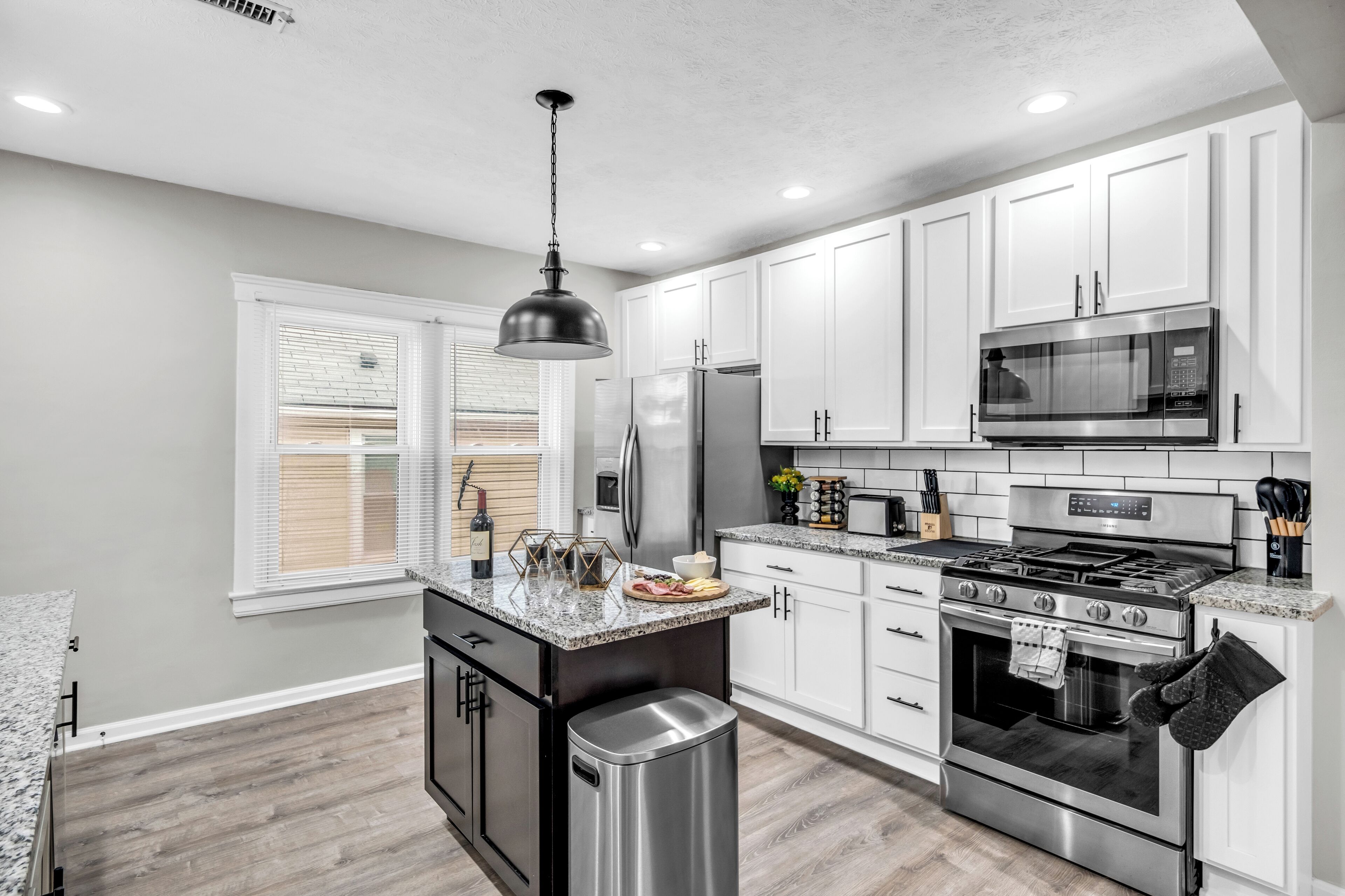 A modern kitchen with white cabinets, stainless steel appliances, and a granite countertop.