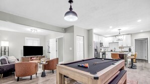 Een moderne woonkamer met een biljart, een bank en een televisie.