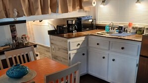 A compact kitchen with white cabinets, a wooden dining table, and a window with blinds. - Classic  2-bedroom , cabin yacht ,house boat ,in the bayou Springfield La (Springfield)