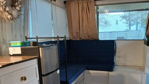A compact kitchen with a refrigerator, a small cabinet, and a window with curtains. - Classic  2-bedroom , cabin yacht ,house boat ,in the bayou Springfield La (Springfield)