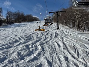 A snowy ski slope with a ski lift and tracks.