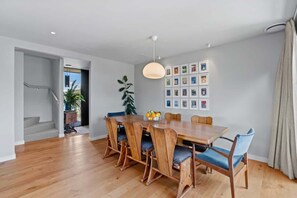 Ein Essbereich mit Holztisch, Stühlen, einer Hängelampe und gerahmten Bildern an der Wand.