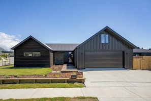 Ein modernes, zweistöckiges Haus mit Garage, Steinaußenwand und gepflegtem Rasen.