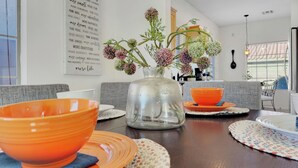 A dining area with a wooden table, orange bowls, and a decorative vase with flowers. - 3BR w patio, community pool, dog friendly (Chandler)