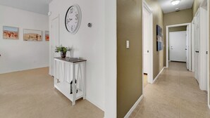 A hallway with a white wall, a clock, and a small table with a plant. - 3BR w patio, community pool, dog friendly (Chandler)